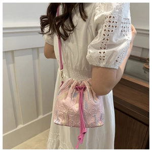 Pink nylon drawstring bucket bag with floral embroidery detail and slim strap