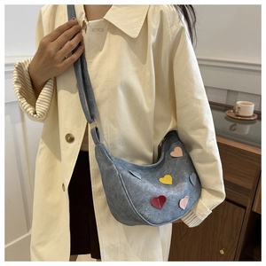 Detail of grey crescent shoulder bag with colorful heart patches on soft trench coat