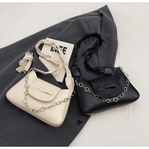Detail of shoulder bags with bow decoration and floral metal chain on a blazer background