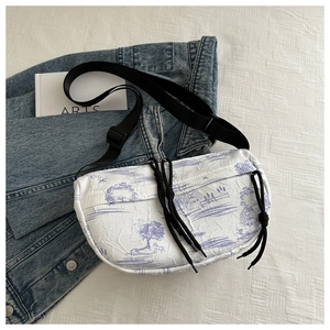 Close-up of pleated tie-dye crescent bag with landscape pattern and long zipper pull