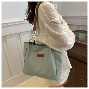 Detail of mint green nylon tote bag with leather logo tag and chain shoulder strap