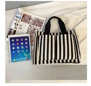 Detail shot of striped canvas tote bag showing double pockets and brown fashion label