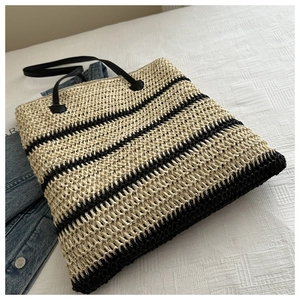 Gros plan du sac cabas en paille tissée avec rayures noires et poignées robustes