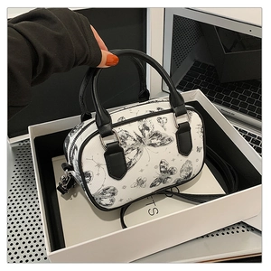 Detail of white butterfly print handbag with black handles and detachable shoulder strap