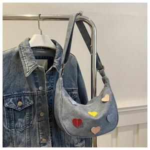 Detail of light blue denim hobo bag with colorful heart patches and adjustable strap