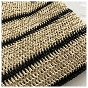 Gros plan du sac seau en paille montrant la texture tissée et les rayures noires