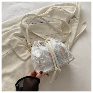 Detail of white nylon bucket bag featuring colorful wave embroidery and gold hardware