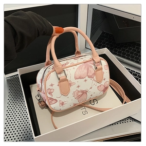 Detail showing the mini butterfly print Boston bag with pink handles and adjustable strap