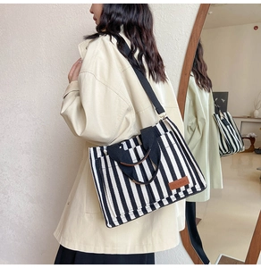Detail of striped canvas tote bag showing large capacity and adjustable crossbody strap