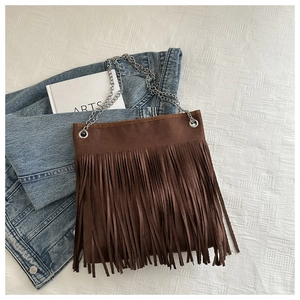 Détail du sac en daim marron avec franges et chaîne argentée sur veste en jean