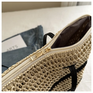 Détail du sac seau en paille avec fermeture éclair et bandoulière en cuir noir