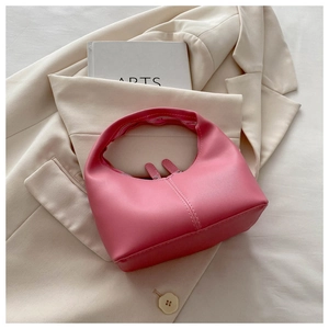 Detail of a pink crescent hobo bag featuring dual metal zippers on a blazer backdrop