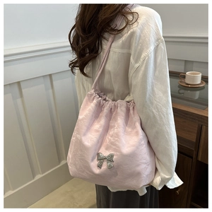Detail of light pink pleated shoulder bag with silver metallic butterfly and strap