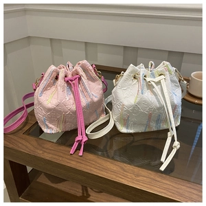Detail of embroidered monogram bucket bags with drawstring and long shoulder straps