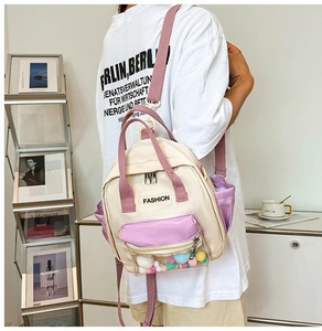 Dettaglio mini zaino in nylon crema e lavanda con tasca in PVC trasparente e pompon