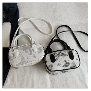 Close-up of mini butterfly print Boston bag with elegant handles and shoulder strap