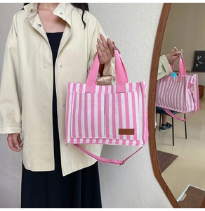 Detail of pink and white striped canvas tote bag showing side view and fashion leather label