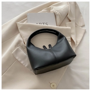 Detail of a black hobo handbag with dual zippers and stitching on a beige blazer