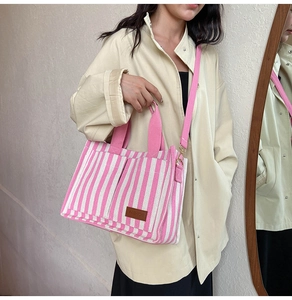 Detail of striped canvas tote with adjustable strap and leather fashion label
