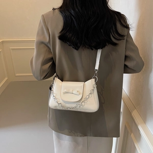 White leather shoulder bag with a bow and silver floral chain shown on a model