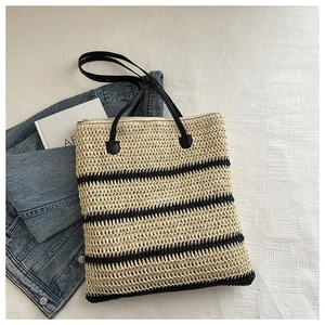 Détail du sac cabas en paille tissée avec rayures noires et anses en cuir noir