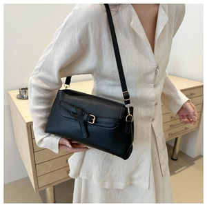 Minimalist black crossbody bag worn by model showing vintage texture and gold buckle
