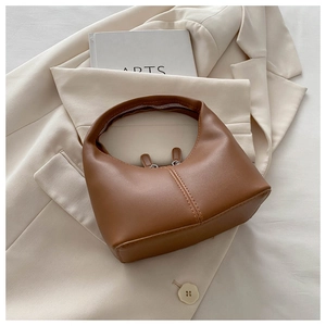 Detailed view of caramel brown PU leather crescent handbag with elegant vertical stitching