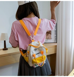 Dettaglio di mini zaino in tela con patchwork giallo e tasca trasparente con pompon
