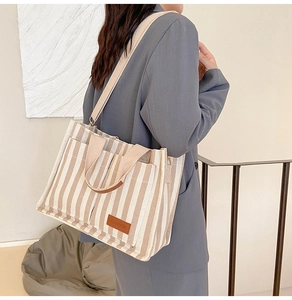 Striped canvas tote bag styled with gray suit for a professional commute look