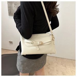 Détail d'un sac bandoulière crème avec boucle de ceinture porté par un mannequin