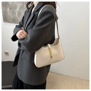 Close-up of cream leather hobo bag with a distinctive gold piston lock on the front