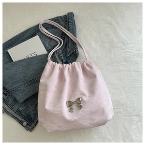 Detail of pink pleated crossbody bag featuring a silver metal butterfly and drawstring