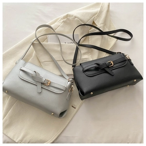 Detail of silver and black leather crossbody bags with gold knotted buckle strap closure