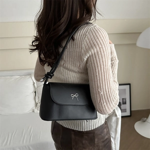 Chic black crossbody bag with silver bow decoration and adjustable shoulder strap