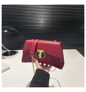 Détail du sac à bandoulière en cuir rouge foncé brillant avec fermoir doré et chaîne