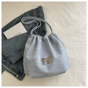 Detail of light blue pleated bucket bag with silver metal bow and drawstring closure