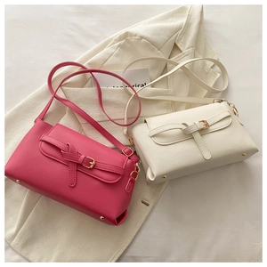 Detail of rose red and beige crossbody bags showing textured faux leather and gold buckles