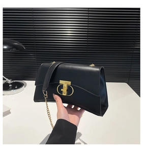 Détail d'un sac à main en cuir noir avec un fermoir métallique anneau en T doré