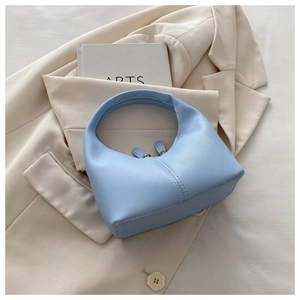 Close-up of light blue crescent handbag with dual zippers on beige suit jacket