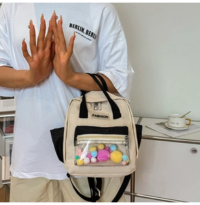 Dettaglio dello zaino in nylon con tasca trasparente e decoro con palline di peluche