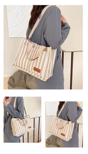 Detailed view of a striped canvas tote bag with adjustable strap and leather patch