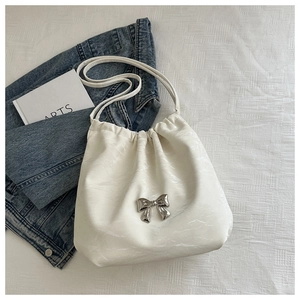 Close-up of white pleated tote bag featuring a metallic silver butterfly and drawstring detail