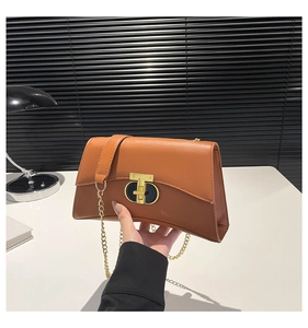 Détail du fermoir doré en T et de la chaîne sur un sac à main marron élégant