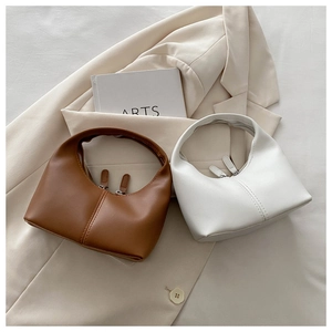 Detail view of brown and white faux leather hobo bags with vertical stitching and zippers