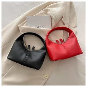 Detail of half-moon leather handbags in black and red with dual zipper closure