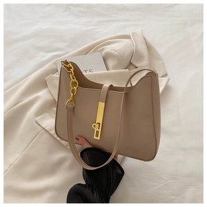 Detail of beige faux leather tote with golden metal lock and chain strap on light background
