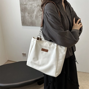 Modern white minimalist tote bag with brown leather accents and silver chain strap