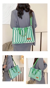 Detail of green and white striped canvas tote bag showing the side view on a model