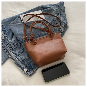 Detail of a brown lychee pattern bucket bag featuring knotted handles on denim jacket