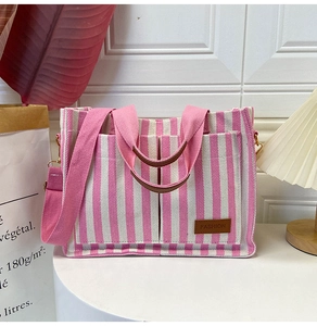 Detail of pink striped canvas tote bag showing front pockets and leather fashion label